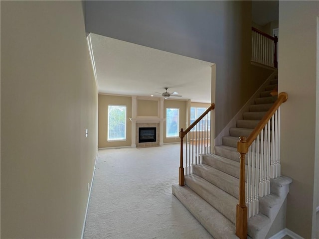 stairway featuring a ceiling fan, baseboards, carpet flooring, and a tiled fireplace