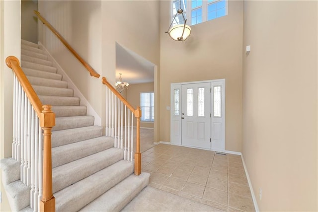 foyer with a towering ceiling, an inviting chandelier, stairs, and baseboards