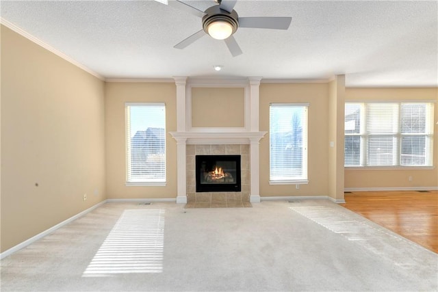 unfurnished living room with ornamental molding, plenty of natural light, a fireplace, and a textured ceiling