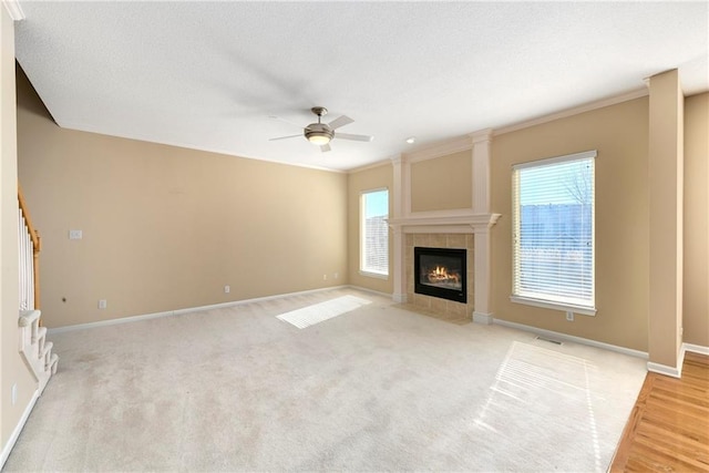 unfurnished living room with a wealth of natural light, visible vents, stairway, and a tiled fireplace