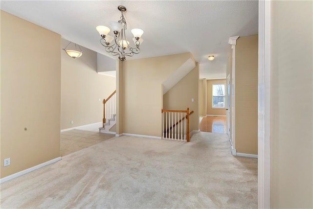 empty room featuring carpet floors, an inviting chandelier, and baseboards