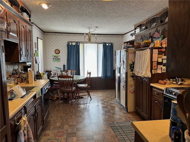 kitchen with dark parquet flooring, black appliances, dark brown cabinetry, and a textured ceiling