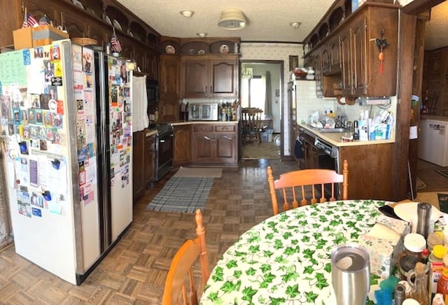 kitchen featuring white fridge, dark brown cabinets, stainless steel microwave, stove, and dark parquet flooring