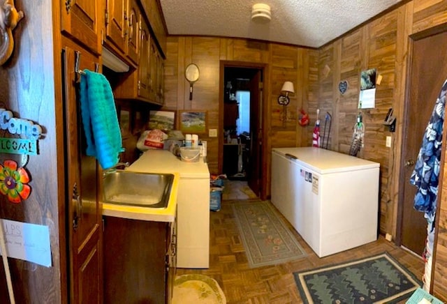 interior space featuring light parquet floors, sink, a textured ceiling, and wooden walls