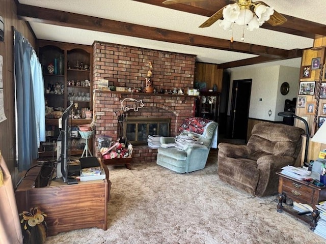 carpeted living room featuring beamed ceiling, ceiling fan, a brick fireplace, a textured ceiling, and brick wall