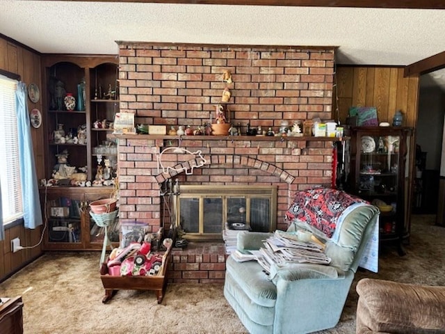 living room with wooden walls, a textured ceiling, a brick fireplace, and carpet floors