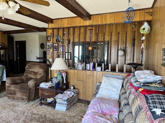 interior space featuring beamed ceiling, ceiling fan, carpet, a textured ceiling, and wood walls