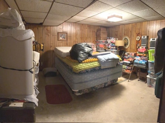 carpeted bedroom with a paneled ceiling and wood walls