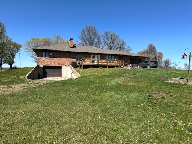 back of property featuring a deck, a yard, and a garage