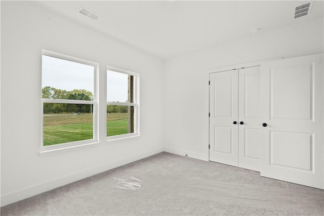 unfurnished bedroom featuring light carpet and a closet