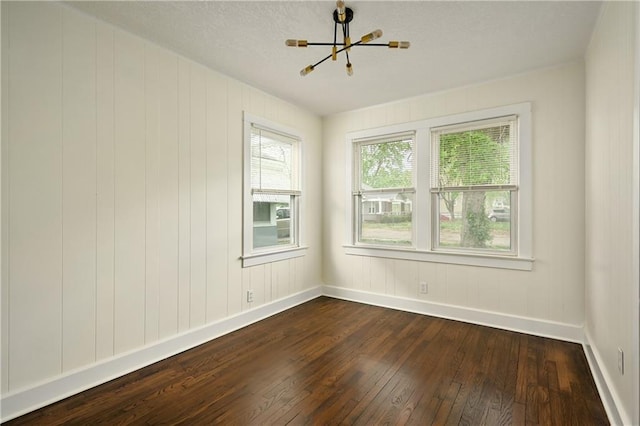 unfurnished room with dark hardwood / wood-style flooring and a notable chandelier