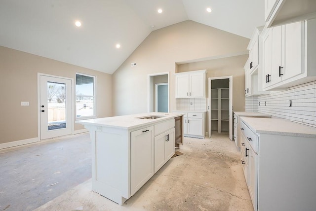 kitchen with dishwasher, vaulted ceiling, an island with sink, white cabinets, and tasteful backsplash