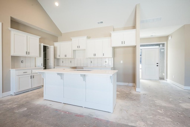 kitchen with a center island, tasteful backsplash, high vaulted ceiling, white cabinetry, and a kitchen breakfast bar