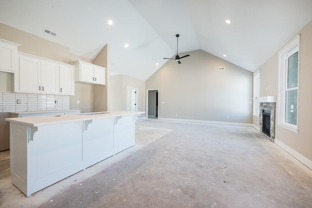 kitchen with a kitchen breakfast bar, a center island, ceiling fan, a fireplace, and white cabinetry