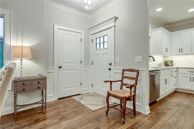 entrance foyer with crown molding, sink, and hardwood / wood-style floors