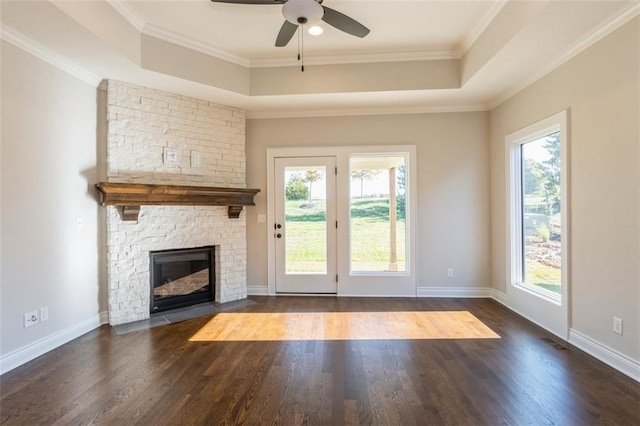 unfurnished living room with crown molding, a stone fireplace, dark hardwood / wood-style floors, and ceiling fan