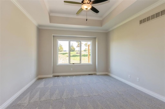 spare room featuring ornamental molding, ceiling fan, light colored carpet, and a raised ceiling