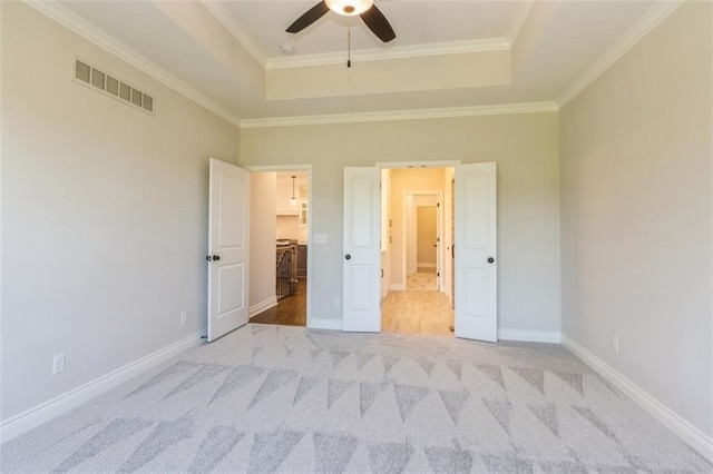 unfurnished bedroom with light carpet, ornamental molding, a raised ceiling, and ceiling fan