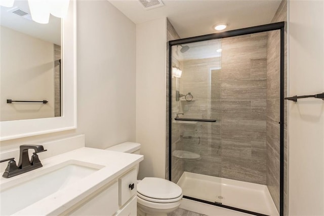 bathroom featuring toilet, vanity, and a shower with door