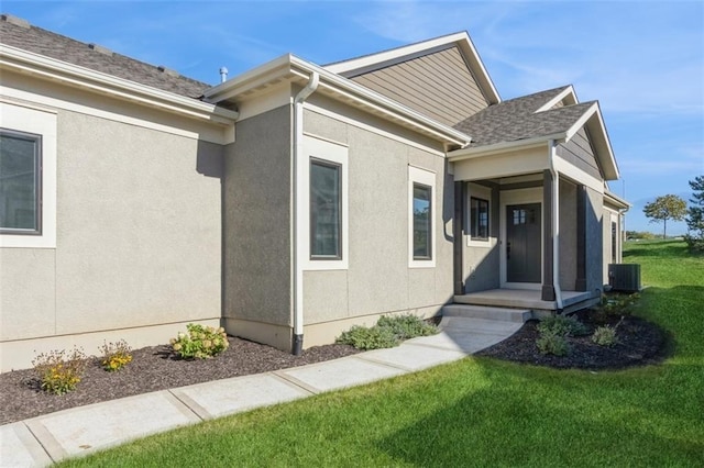 doorway to property featuring central air condition unit and a lawn