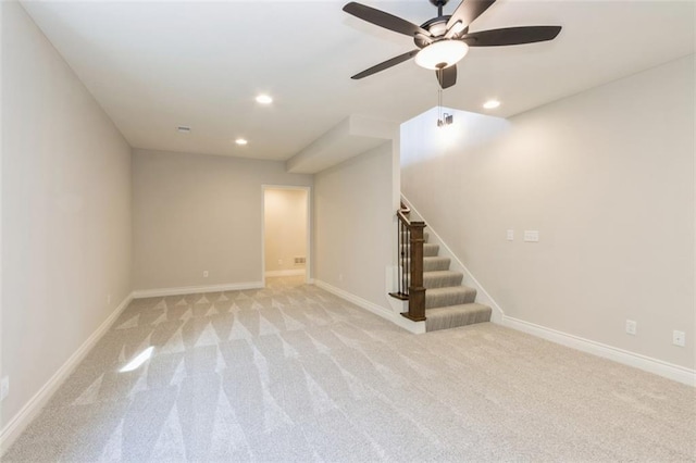 basement with ceiling fan and light colored carpet