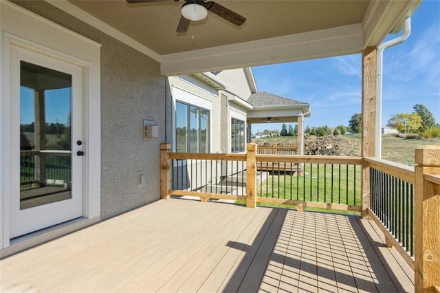 wooden terrace with ceiling fan and a lawn