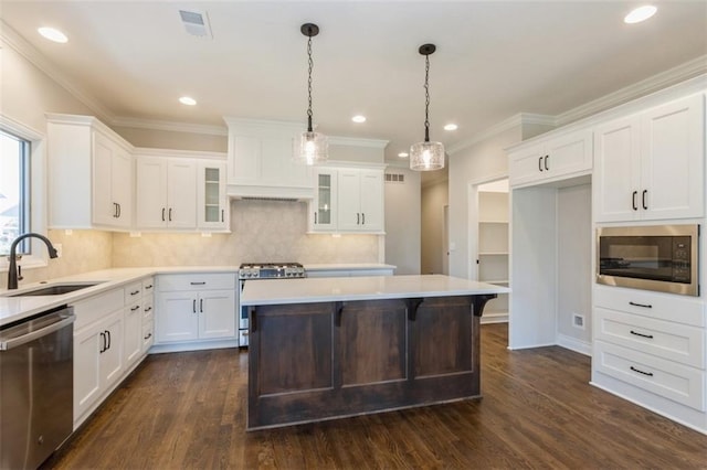 kitchen with appliances with stainless steel finishes, sink, a center island, white cabinetry, and dark wood-type flooring