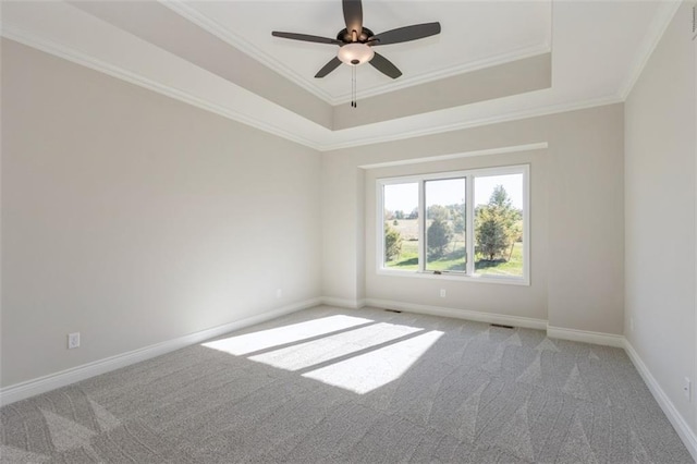 carpeted empty room with crown molding, a raised ceiling, and ceiling fan