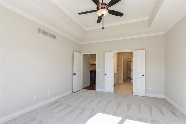 unfurnished bedroom featuring crown molding, a raised ceiling, light colored carpet, and ceiling fan