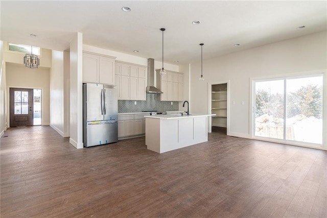 kitchen with light countertops, an island with sink, freestanding refrigerator, and pendant lighting