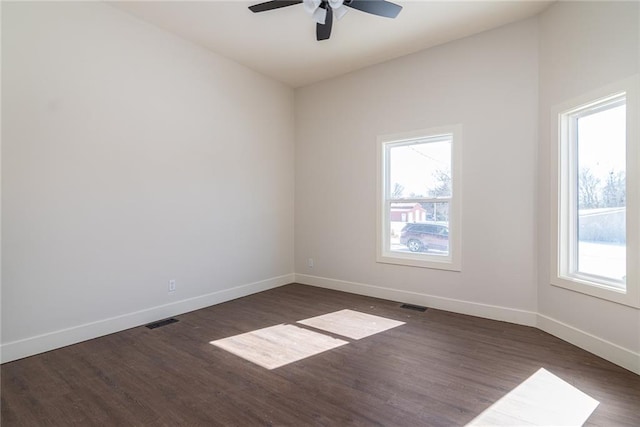 unfurnished room featuring dark wood finished floors, visible vents, and baseboards