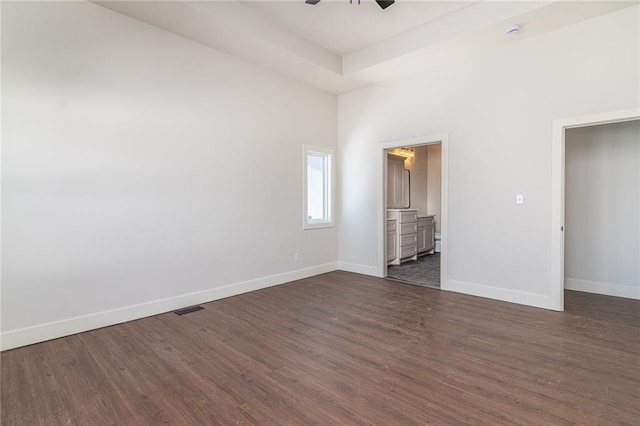 unfurnished bedroom featuring visible vents, baseboards, dark wood finished floors, and a raised ceiling