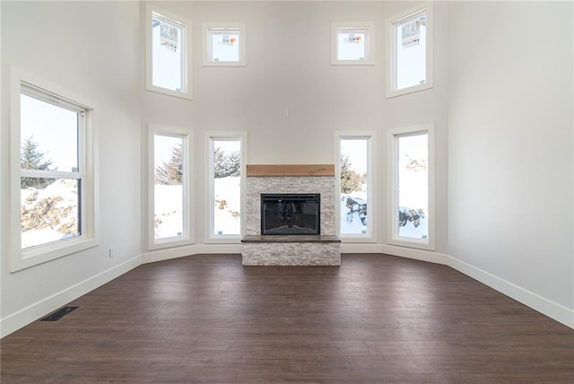 153 S Linn Valley Dr, Linn Valley, KS 66040 - unfurnished living room featuring a stone fireplace, a towering ceiling, dark wood-type flooring, and baseboards
