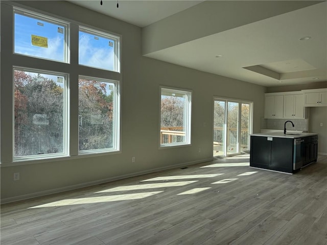 kitchen featuring dishwasher, decorative backsplash, light hardwood / wood-style flooring, and white cabinetry