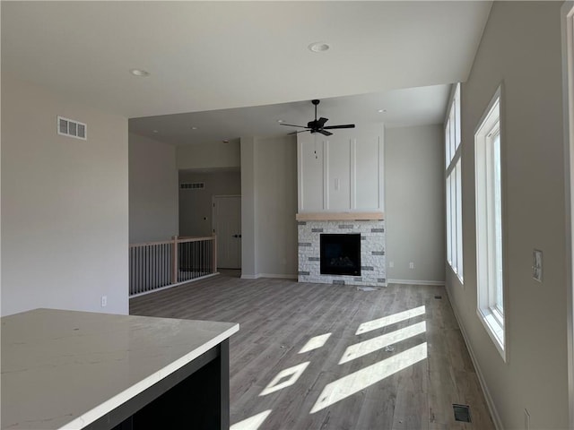 unfurnished living room with ceiling fan, a fireplace, and light hardwood / wood-style flooring