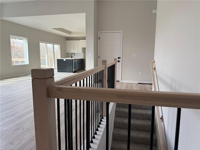 stairs with hardwood / wood-style floors and a raised ceiling