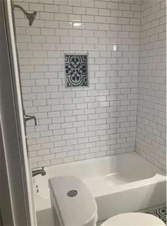 bathroom featuring tiled shower / bath and toilet