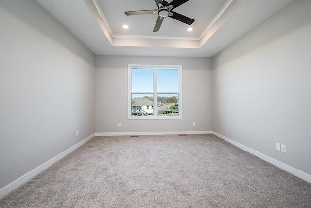 carpeted empty room with ceiling fan, a raised ceiling, and ornamental molding