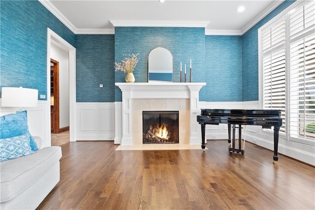 living room featuring wallpapered walls, ornamental molding, a wainscoted wall, and wood finished floors