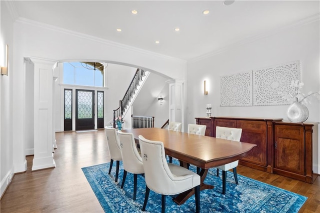 dining space with crown molding, stairway, wood finished floors, and ornate columns