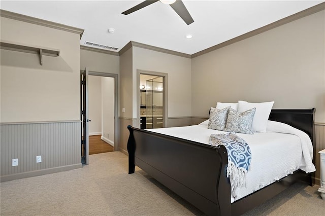 bedroom featuring visible vents, a wainscoted wall, crown molding, light colored carpet, and a ceiling fan