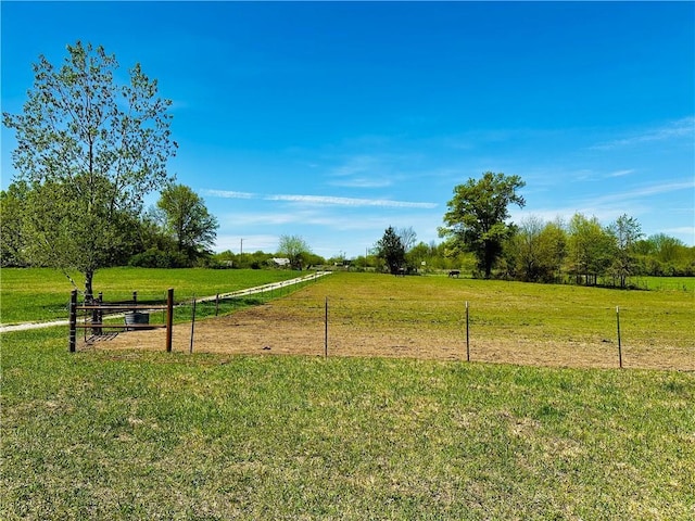 view of community with a rural view, a lawn, and fence