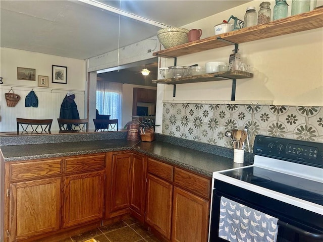 kitchen with range with electric cooktop, dark tile patterned floors, open shelves, dark countertops, and brown cabinetry