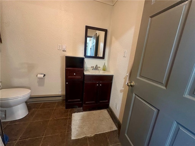 half bathroom with vanity, baseboards, tile patterned floors, toilet, and baseboard heating