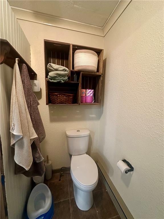 bathroom with tile patterned floors, toilet, and a textured wall