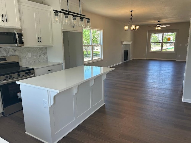 kitchen with dark hardwood / wood-style flooring, white cabinets, stainless steel appliances, and a kitchen island