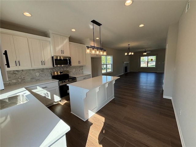 kitchen with decorative backsplash, dark hardwood / wood-style flooring, stainless steel appliances, white cabinets, and a center island