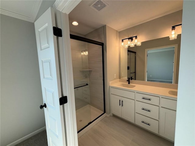 bathroom with a shower with door, vanity, and ornamental molding