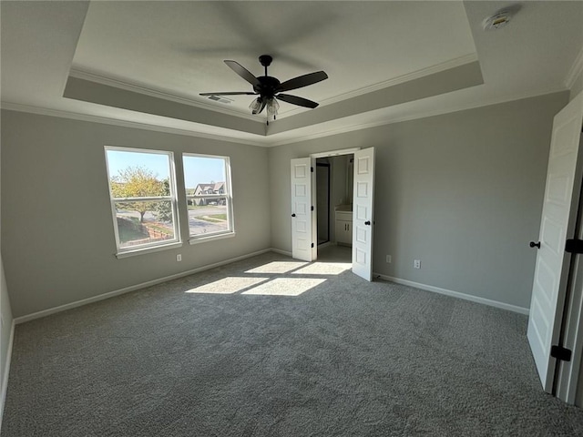 unfurnished bedroom with ceiling fan, a raised ceiling, carpet floors, and crown molding