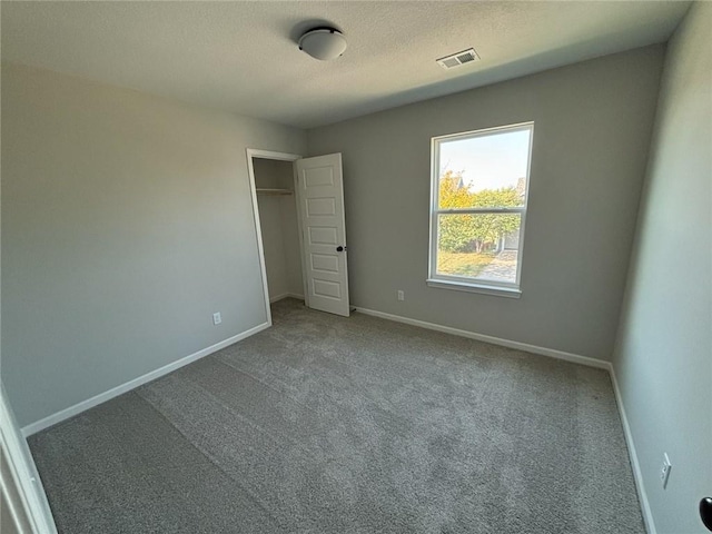 unfurnished bedroom with a closet, carpet, and a textured ceiling